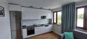 a kitchen with white cabinets and a stainless steel refrigerator at Apartament Choszczno in Choszczno