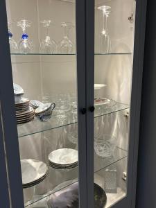 a glass cabinet filled with plates and glasses at Lena Apartment Tromsø in Kvaløya