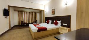 um quarto de hotel com uma cama grande com almofadas vermelhas em Sapphire luxury Suites em Ooty