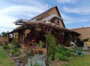 uma casa com toldo e flores num quintal em Holt-Tisza Vendégház em Szeged