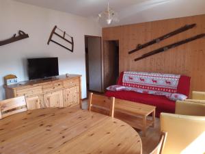 a living room with a table and a red couch at Appartement Le Parad'hiver in Gérardmer
