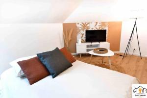 1 dormitorio con 1 cama blanca y TV en L’envol Temporaire Seh’Loué, en Saint-Brieuc