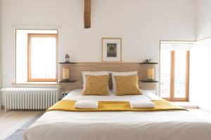 a white bedroom with a large bed with two windows at La Petite Cour in Villiers-sous-Grez