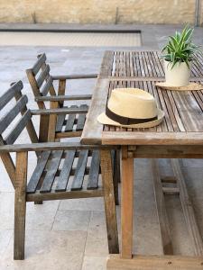 a wooden picnic table with a hat on it at La Petite Cour in Villiers-sous-Grez