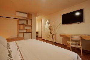 a bedroom with a bed and a desk and a television at Hotel Materia in Oaxaca City