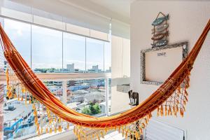 a hammock hanging in a room with a large window at WI-FI 100mb | Vista Parcial do MAR #CA32 in Florianópolis