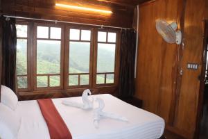 two swans on a bed in a room with a window at spice garden Resorts munnar in Anachal +7 photos