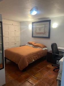 a bedroom with a bed and a desk and a chair at Encantador loft! por el lago in Juriquilla