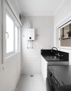 een witte badkamer met een wastafel en een raam bij Apartamento da Rota Gastronômica de Bento Gonçalves in Bento Gonçalves