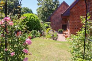 un jardín con flores rosas y un edificio de ladrillo en A magical countryside retreat en New Alresford