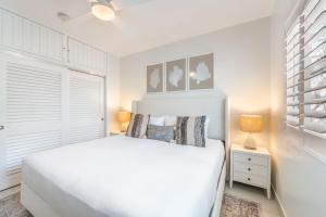 a white bedroom with a white bed and a window at Villas of the Galleon #6 in Seven Mile Beach