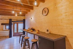 a kitchen with wooden walls and a counter with stools at Le Chalet in Saint-Pardoux-la-Rivière