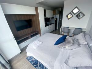 een slaapkamer met een groot wit bed met blauwe kussens bij Apartaestudios modernos y exclusivos en Bogotá in Bogota