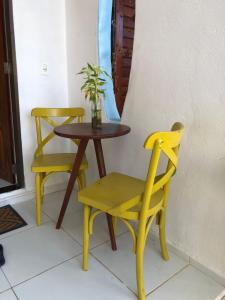 einen Tisch und zwei gelbe Stühle sowie einen Tisch und einen Stuhl in der Unterkunft Pousada Paracuru Surf in Paracuru