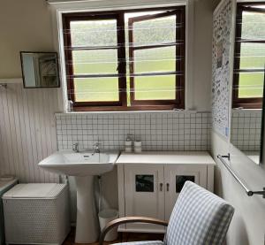uma casa de banho com um lavatório, uma janela e uma cadeira em Stok&Hoed em Natureʼs Valley