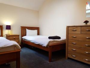 a bedroom with two twin beds and a dresser at Peregrine Stable Cottage in Llandovery