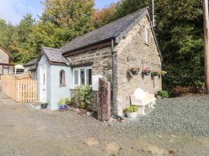 ein kleines Steingebäude mit einer Bank davor in der Unterkunft Pendre Cottage in Llanfyrnach