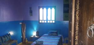 - une chambre bleue avec un lit et une fenêtre dans l'établissement DAR OUZOUD Vegan, à Ouzoud
