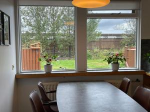 a dining room with a table and two windows at Airport Comfort Home in Njarðvík