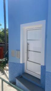 a white door on the side of a blue building at Tides proprety - Low tide in Paul do Mar