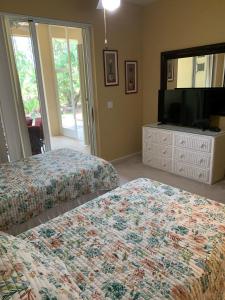 a bedroom with two beds and a flat screen tv at Right Direction Rentals in Port Saint Lucie