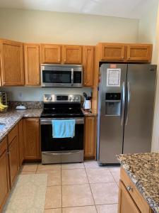 a kitchen with stainless steel appliances and wooden cabinets at Right Direction Rentals in Port Saint Lucie