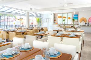 un ristorante con tavoli in legno e sedie bianche di Hotel Palace 1 a Florianópolis