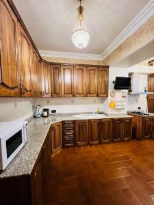 a kitchen with wooden cabinets and a white microwave at Superb Central Location! Spacious and Comfortable 1 Bedroom + Jacuzzi, Next To Northern Avenue in Yerevan