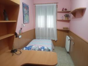 a small bedroom with a bed and a desk at Can Molone in Cornudella