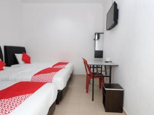 a room with two beds and a desk with a television at Hotel De'light Villa in Kota Bharu