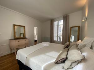 a bedroom with a large white bed and two mirrors at Aux Terrasses de la Lune in Paris