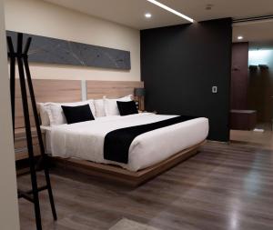 a bedroom with a large white bed with black and white pillows at Domun Hotel in Querétaro