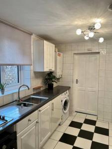 una cucina con armadi bianchi e pavimento a scacchi in bianco e nero di Holiday Home in Walthamstow a Londra