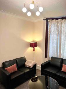 una sala de estar con 2 sofás negros y una lámpara. en Holiday Home in Walthamstow en Londres