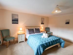1 dormitorio con 1 cama con sábanas azules y 2 sillas en Little Pines, en Scarborough