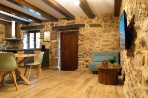 a room with a stone wall and a table and chairs at Ecolagar O Barqueiro in Pantón