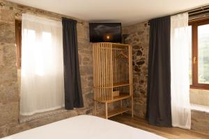 a bedroom with a bed and a tv on a stone wall at Ecolagar O Barqueiro in Pantón