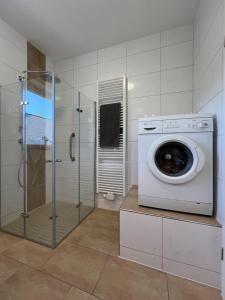 a washing machine in a bathroom with a shower at Schöne Ferienwohnung im Grünen - 5 Minuten vom Schloss Dankern entfernt in Haren