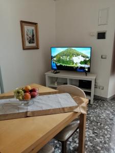 un soggiorno con TV e tavolo con cesto di frutta di Casa Vacanze Patrizia a Montescaglioso