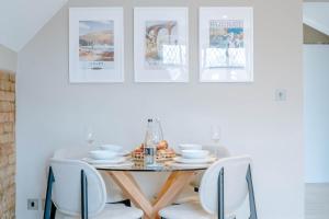 a dining room table with white chairs and pictures on the wall at Spring Grove Apartment - Central Harrogate in Harrogate
