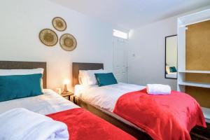 1 dormitorio con 2 camas y manta roja en Airport Way - Cosy 2 Bed Apartment near the M1, en Luton