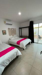 a bedroom with two beds with pink and white sheets at Casa de Descanso y Aventuras en zona privada in Mérida