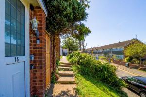 a brick house with a sidewalk next to a tree at Airport Way - Cosy 2 Bed Apartment near the M1 in Luton