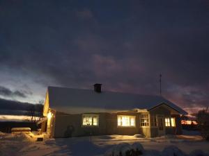 una casa con sus luces encendidas en la nieve en Vanha maalaistila, en Kuhmo
