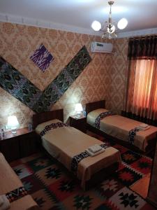 a hotel room with two beds and a rug at Khiva Bibimariyam in Khiva
