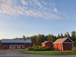 un par de graneros rojos en un campo con árboles en Vanha maalaistila, en Kuhmo