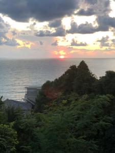 a sunset over the ocean with trees and a building at Guesthouse Eco Chakvi in Chakvi