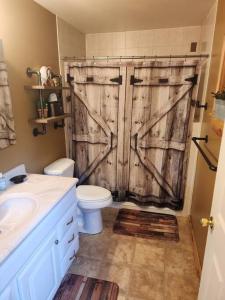 a bathroom with a wooden door with a toilet and a sink at 2 bed, 1.5 bath cottage across from Watauga Lake in Butler