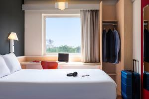 a hotel room with a bed and a window at Ibis Guadalajara Expo in Guadalajara