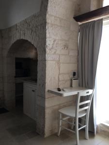 a table and a chair in a room with a stone wall at TRULLI LE 2 NICCHIE in Locorotondo